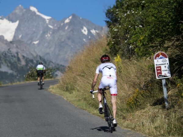 Deux cyclistes sur route pédalent pour le col du Granon, un des cols mythiques du cyclisme des Alpes.