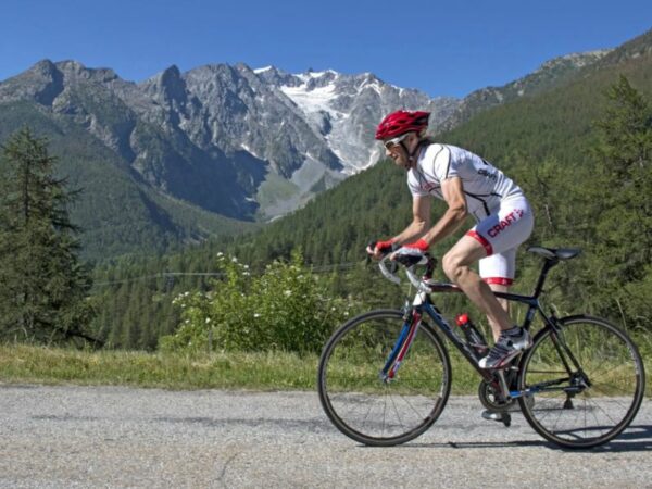Un cycliste sur route de profil qui tente le col alpin du Lautaret, un itineraire tour de France.